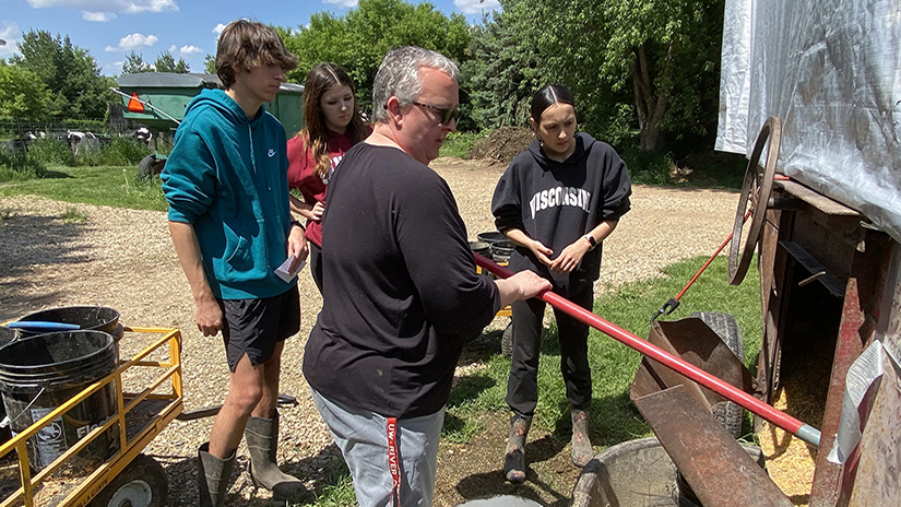 New Richmond High School agriscience teacher Rachel Sauvola shovels corn from a gravity box as she instructs students