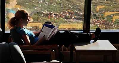 A student reading in an armchair in front of a window