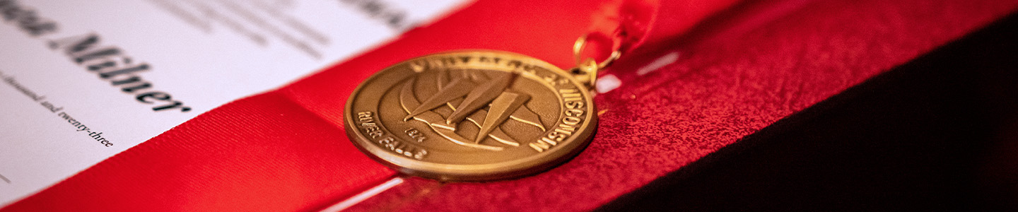 A gold medal with red ribbon sit on a table