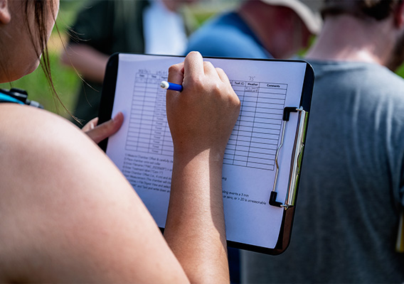 A female student writes down data on a clipboard