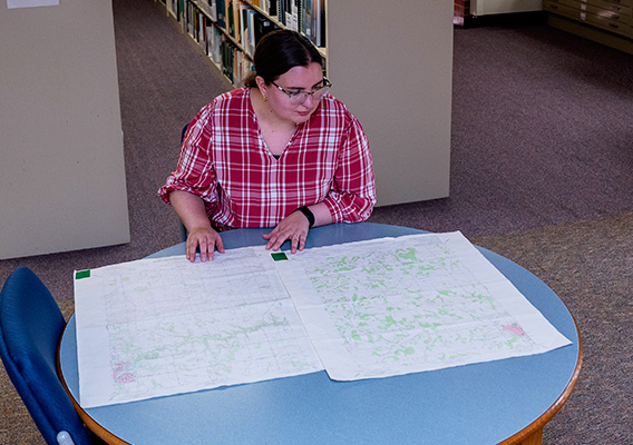 A student looks at topographical maps in the library
