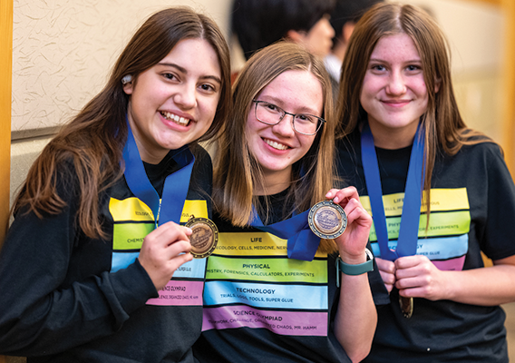 three students displaying their Science Olympiad medals