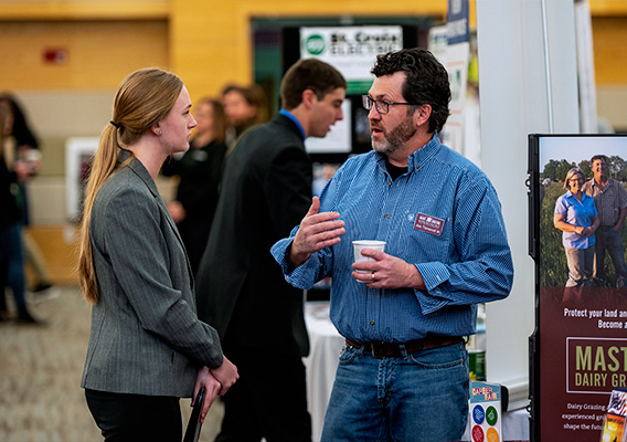 A female student speaks to an employer at the career fair