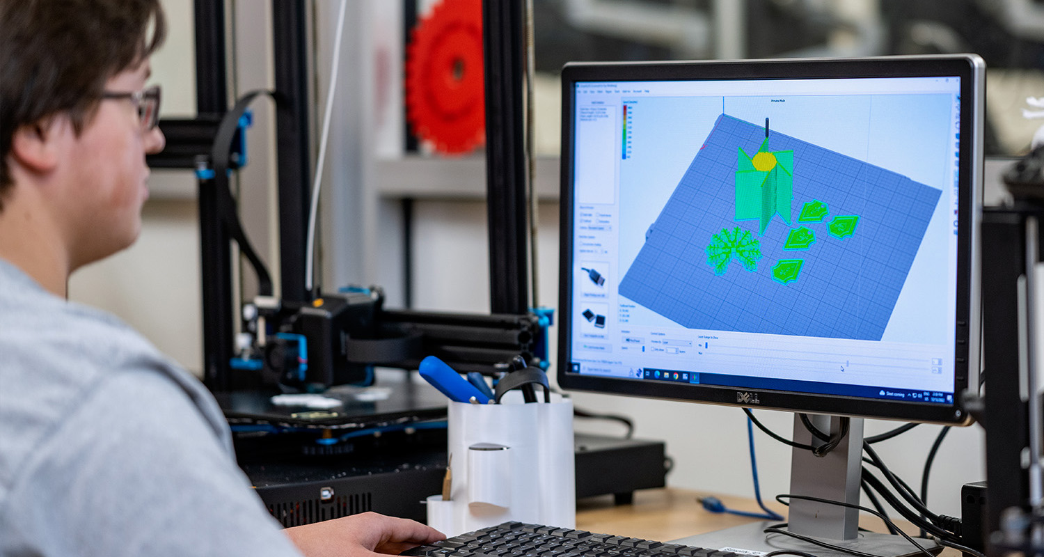 A male student uses a 3D Imaging software to create an object to print on a 3D printer.