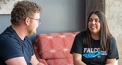 Two students sit and talk to one another in the Falcon's Nest in the UC