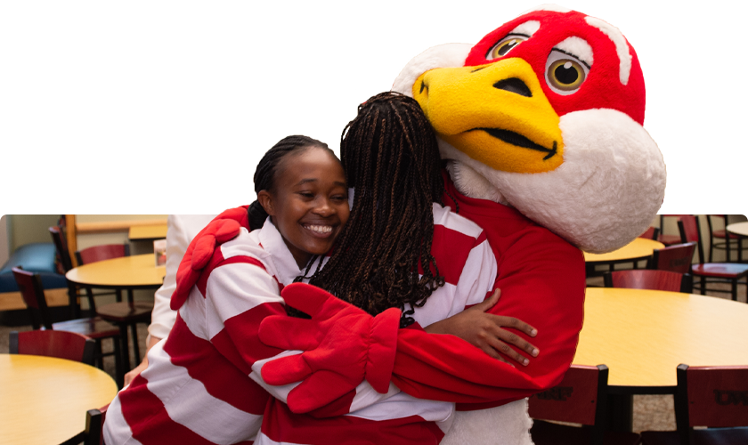 Two students hug Freddy Falcon in the UC