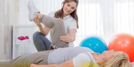 physical therapy aide helping a patient stretch