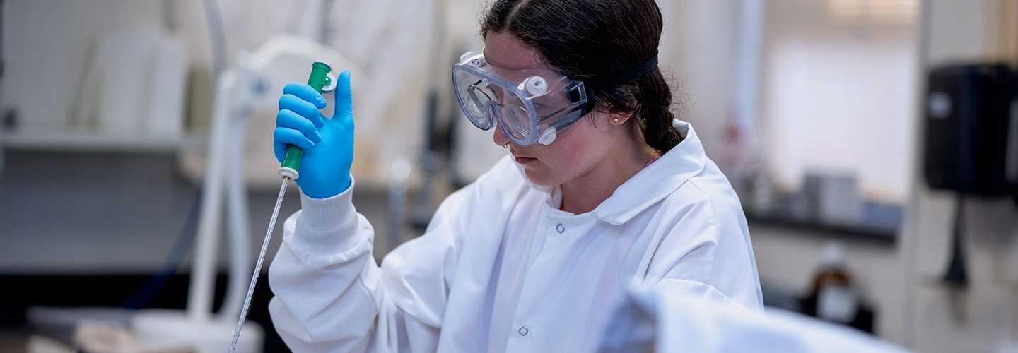 A female student uses a pipette in their science lab